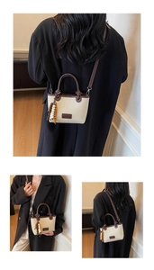 Detail of beige canvas bucket bag with brown leather trim and stylish wooden bead charm