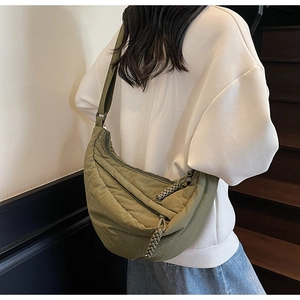 Detail of an olive green nylon crescent bag featuring a textured finish and woven zipper pull