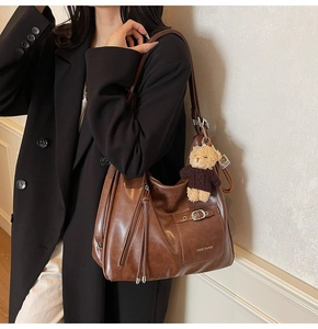 Gros plan sur un grand sac cabas marron rétro avec logo ZSKE PARIS et breloque ours en peluche