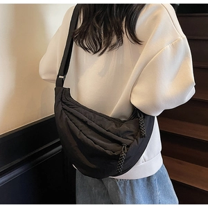 Detail of black nylon dumpling bag with pleated texture and adjustable wide shoulder strap