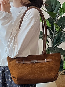 Borsa a secchiello in camoscio marrone con fibbia argento indossata da una modella