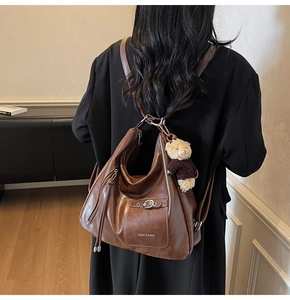 Détail d'un sac hobo en cuir marron avec logo ZSKE PARIS et un pendentif ours en peluche
