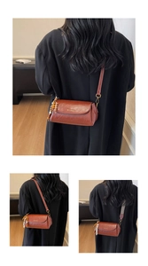 Détail du sac bandoulière marron foncé en similicuir avec logo et pendentif perlé