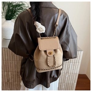 Detail of beige suede and leather backpack with gold clasp and woven chain strap