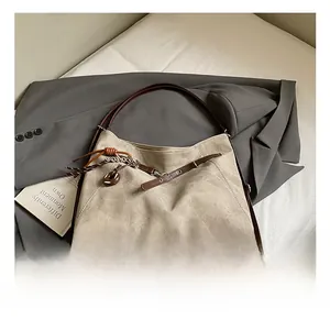 Close-up of beige tote bag with brown leather straps and decorative tassel pendant