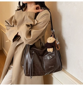Grand cabas marron avec charme d'ours en peluche porté par un mannequin en trench-coat