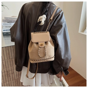 Detail of beige suede and leather bucket backpack with gold chain straps and twist lock