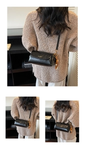 Détail d'un sac à bandoulière noir brillant avec breloque en bois et logo métallique