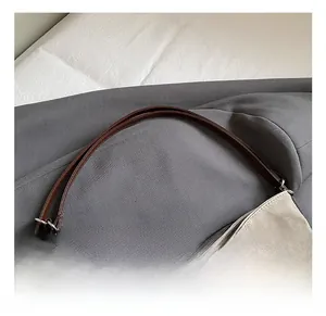 Detail showing the brown leather strap and high-quality canvas texture of the tote bag