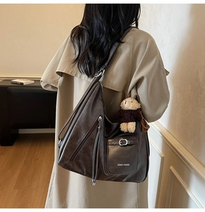 Détail du sac cabas en cuir marron avec fermeture éclair et charm d'ours peluche