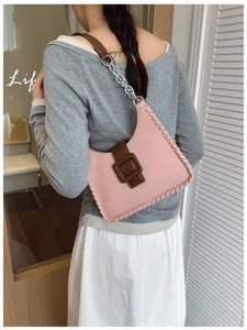 Détail du sac sous l'aisselle en toile rose avec coutures tressées et chaîne en métal