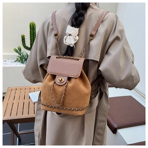 Detail of vintage brown suede backpack with gold metal twist lock and chain strap accents