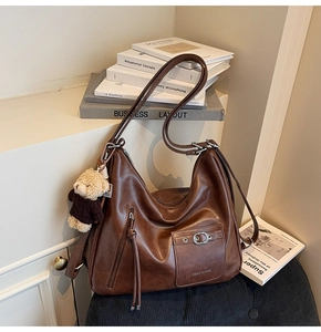 Détail du grand sac cabas marron en cuir synthétique avec lettrage et charm d'ours