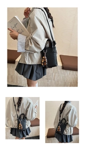 Detail of black woven mini crossbody bag featuring ethnic wooden bead tassel decoration