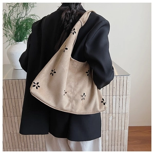 Détail du sac cabas en daim beige avec des motifs floraux découpés au laser sur la bandoulière