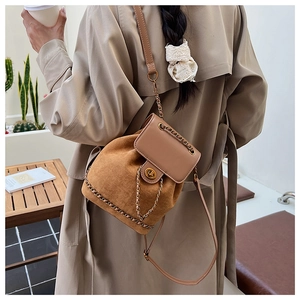 Detail view of vintage brown suede bucket bag featuring chain strap and metal lock closure