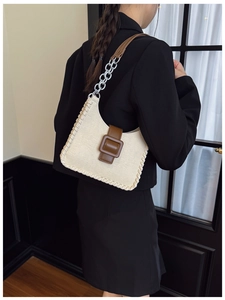 Détail du sac bandoulière contrasté avec boucle en cuir marron et chaîne en métal argenté