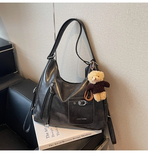 Détail du grand sac hobo noir avec poche à boucle métallique et breloque ours en peluche
