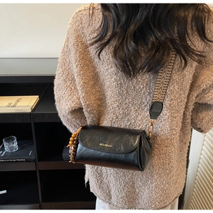 Détail du sac bandoulière vintage en cuir noir avec sangle géométrique et perle en bois