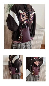 Detail view of burgundy woven texture mini crossbody bag with wooden bead charm accessory