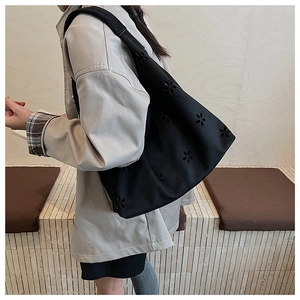 Gros plan détaillé d'un sac cabas noir avec motifs floraux ajourés et texture en suédine