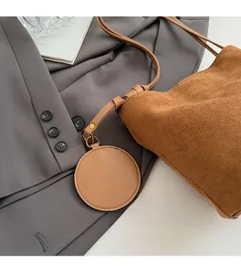 Détail d'un sac seau en daim marron avec cordon de serrage et breloque ronde en cuir stylée