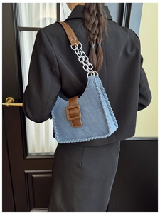 Détail du sac hobo en denim bleu avec bandoulière chaîne sur un blazer noir