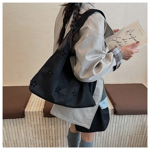 Détail du motif floral découpé au laser sur le sac cabas noir en daim pour femme