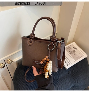 Detailed view of coffee canvas bucket bag with leather trim and beaded ornament