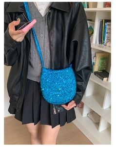 Detail einer blauen Pailletten-Beuteltasche mit Riemen, getragen von einem Model im Alltag