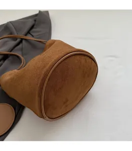 Détail du fond circulaire renforcé sur ce sac seau en daim marron de style minimaliste
