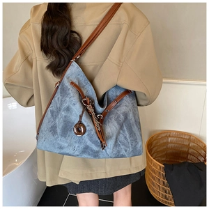 Macro detail of navy blue suede tote bag with brown leather strap and side charm