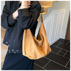 Close-up of light brown suede hobo tote bag featuring minimalist texture and adjustable strap