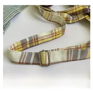 Detail of adjustable plaid shoulder strap with silver metal buckle on tote bag