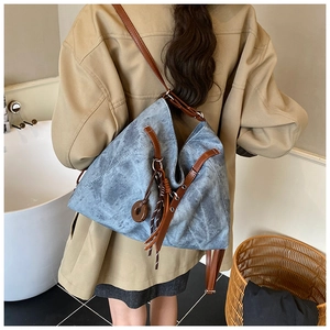 Detail view of vintage blue tote bag with brown leather straps shown on a model
