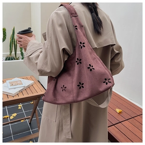 Détail du motif floral découpé au laser sur un sac cabas en daim violet porté