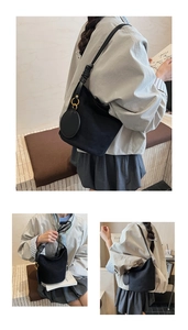 Détail d'un sac seau en daim noir avec design artistique de nœud et anneaux en métal doré