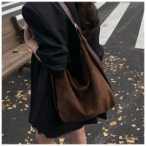 Detail of dark brown suede tote bag with wide shoulder strap and silver metal ring