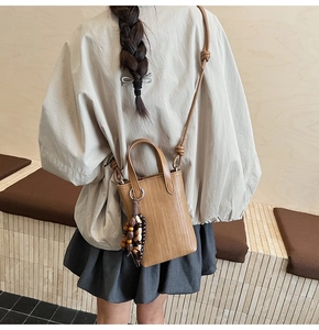 Detailed close-up of brown woven texture mini bag with wooden bead charm accent