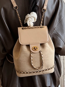 Beige faux suede chain backpack with gold turn-lock closure on model wearing brown jacket