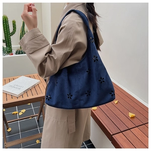 Détails du motif floral découpé au laser sur le sac cabas bleu marine en daim synthétique