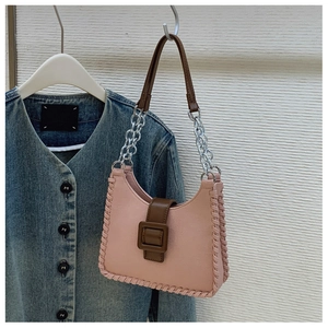 Détail du sac sous le bras en cuir rose avec bords tressés et grande boucle marron
