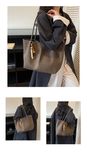 Detail der dunkelolivfarbenen Wildleder-Tote-Bag mit bunten Holzperlen-Quasten und Riemen