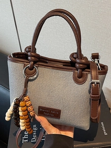 Minimalist grey canvas bucket bag with brown leather handles and decorative wood beads
