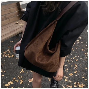 Detailed view of the dark brown suede hobo tote bag worn as a crossbody shoulder bag