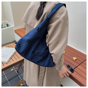 Détail d'un sac cabas en daim bleu marine avec motifs floraux découpés au laser ici