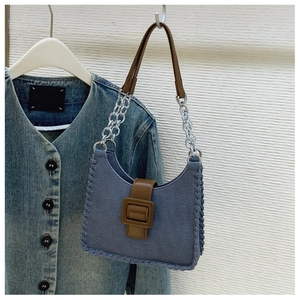Gros plan d'un sac en denim bleu vintage avec bandoulière en cuir brun et chaîne argent