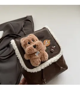 Detail showing plush dog charm and faux shearling trim on brown leather backpack