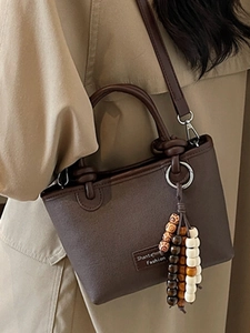 Brown leather bucket bag with wooden bead tassel and adjustable strap shown on model