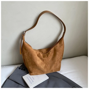 Detail of tan suede hobo bag with adjustable leather strap and silver metal zipper